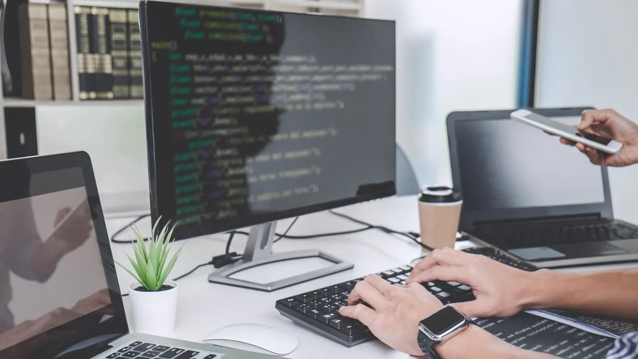 Softwareentwickler am Schreibtisch mit Programmcode auf dem Monitor – Symbolbild für Outplacement in IT und Software